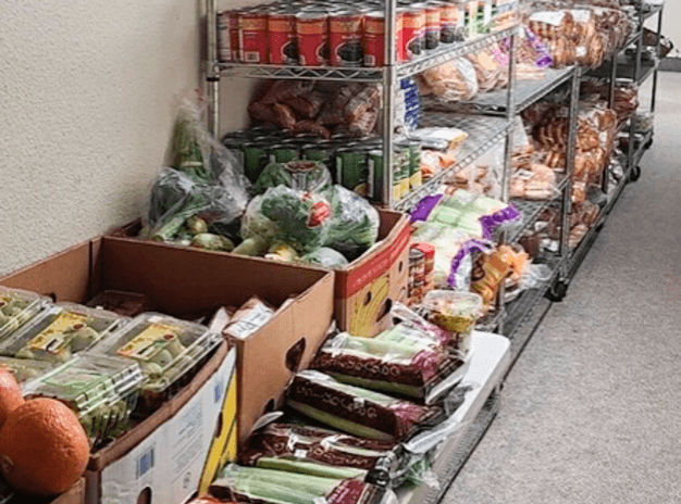 Shelves and boxes filled with fresh vegetables and packaged goods in a market.